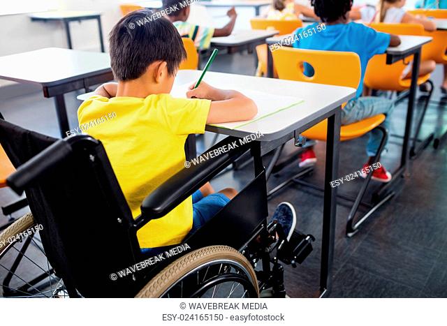 A pupil in wheel chair working at his desk