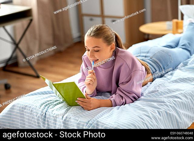 thinking girl with diary lying on bed at home