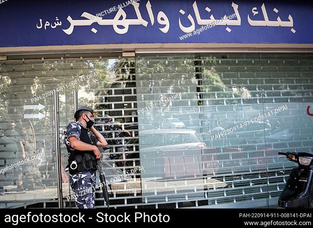 14 September 2022, Lebanon, Beirut: A Lebanese police officer secures the facade of a local bank, after it was stormed by depositors who fled with thousands of...