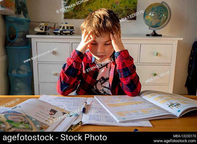 A boy sits at his desk in homeschooling doing chores for school