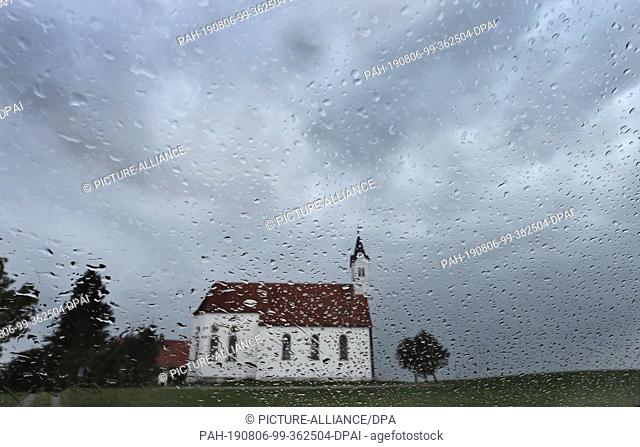 06 August 2019, Bavaria, Aitrang: The pilgrimage church Sankt Alban can be seen behind a rain-wet window. Photo: Karl-Josef Hildenbrand/dpa