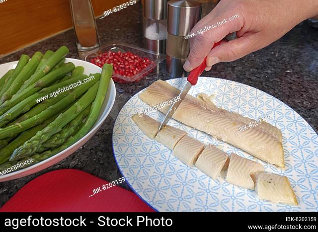 Swabian cuisine, cutting smoked trout, preparing Pfitzauf with asparagus salad and honauforelle, green asparagus, pomegranate seeds, plate, glass bowl