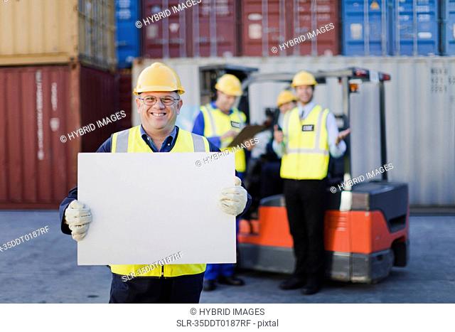 Worker holding sheet in shipping yard