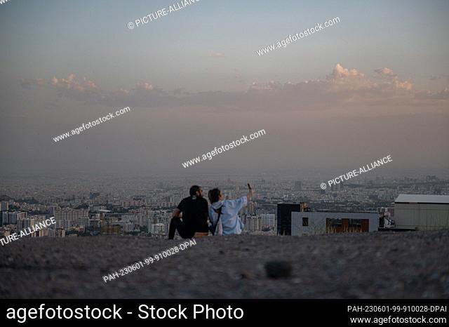 01 June 2023, Iran, Teheran: A young couple takes a selfie in the evening light on a mountain in the east of Tehran, a metropolis of millions