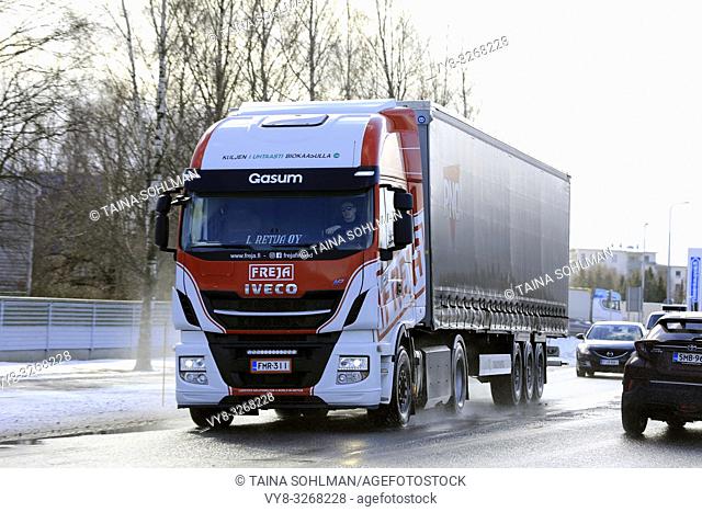 Salo, Finland - March 9, 2019: Biogas fueled Iveco Stralis NP truck L. Retva Oy pulls trailer on wet road among traffic on a day of early spring