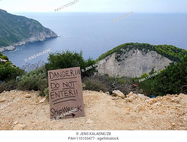 05.10.2018, Greece, Zakynthos: A warning sign ""Danger! Do not enter !!"" stands on the steep coast of Navagio Bay on the Greek island of Zakynthos