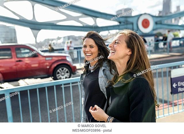 UK, London, two happy women walking on the Tower Bridge