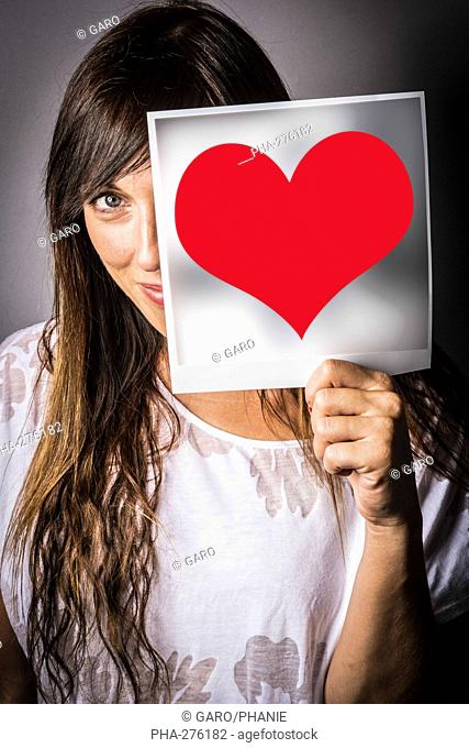 Woman holding heart picture in front of her face