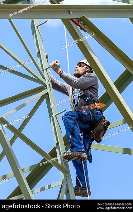 06 July 2020, Saxony, Heidenau: A technician climbs up the power pole to his workplace. In Heidenau near Dresden in Saxony