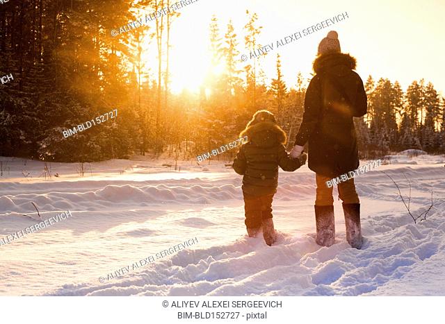 Mother and son walking in snowy forest clearing
