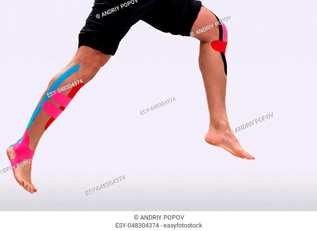 Low Section Of A Man Running With Physio Tape On His Legs Over White Background
