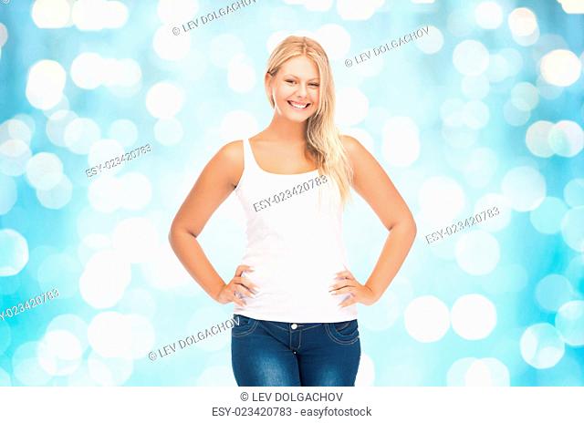 people, holidays, style and body type concept - smiling young woman in blank white shirt and jeans over blue holidays lights background
