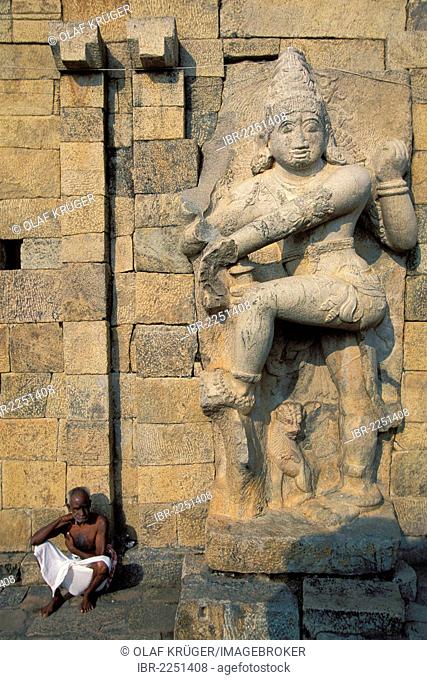 Man sitting beneath a demon statue, Brihadisvara temple, a UNESCO World Heritage site, Gangaikonda Cholapuram, Tamil Nadu, southern India, Asia