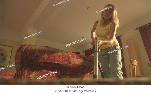 Woman hoovering living room carpet