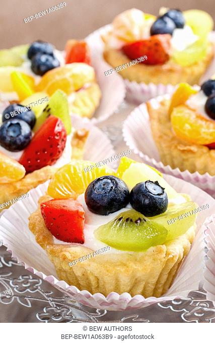 Cupcakes with cram and fresh fruits: strawberry, peach, kiwi, blueberry