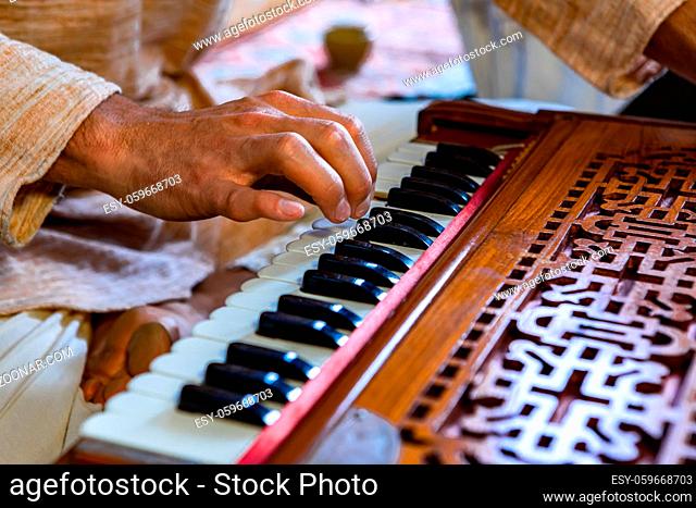 Closeup of shamanic hands pressing harmonium keys playing sacred kirtan music for divine power and spiritual energy to connect with soul