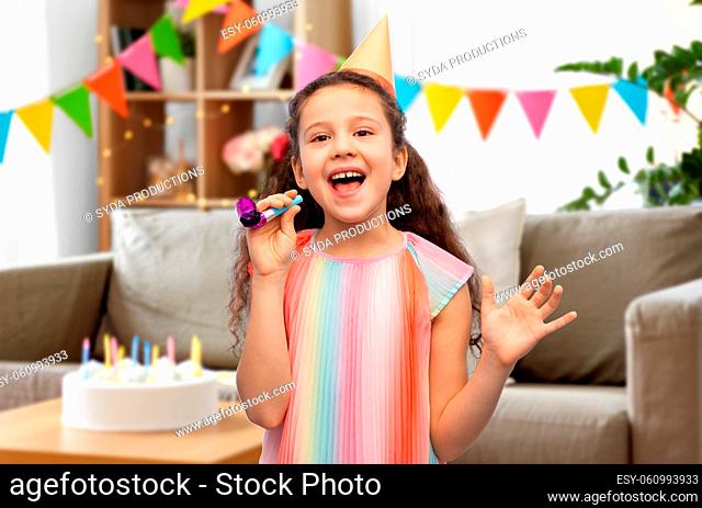 smiling girl in birthday party hat with blower
