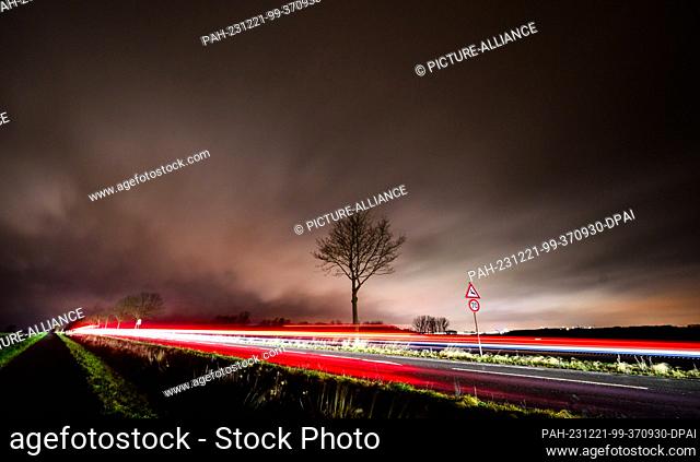 21 December 2023, Lower Saxony, Laatzen: Clouds pass over the Hanover region while cars drive along a country road (long exposure)