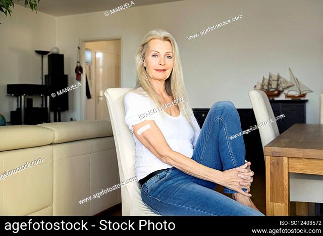 Austria, Viena, mujer mayor con vendaje adhesivo en el brazo sentado en una silla