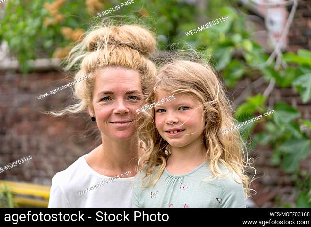 Smiling blond woman with daughter at back yard