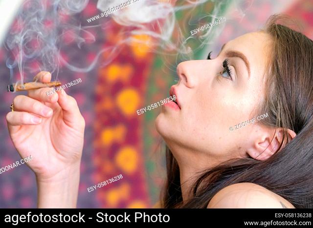 A beautiful brunette model smokes marijuana in the privacy of her own home