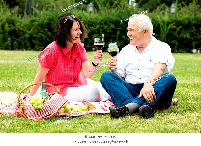 Smiling Senior Couple Drinking Wine In Park