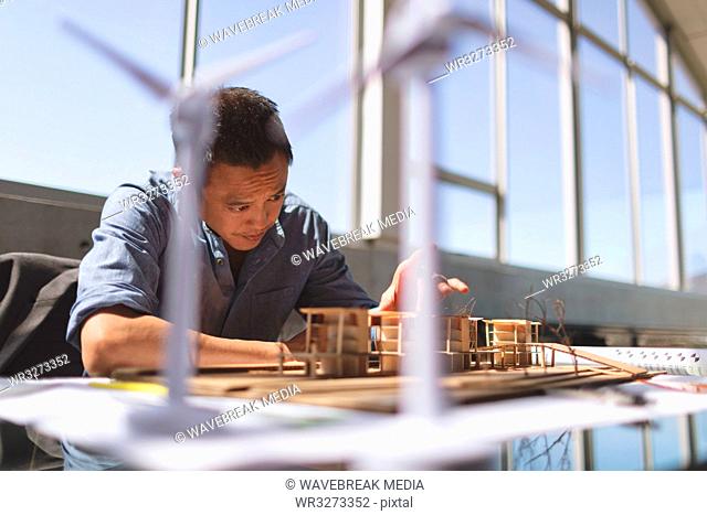 Male architect working on architectural model at desk in a modern office
