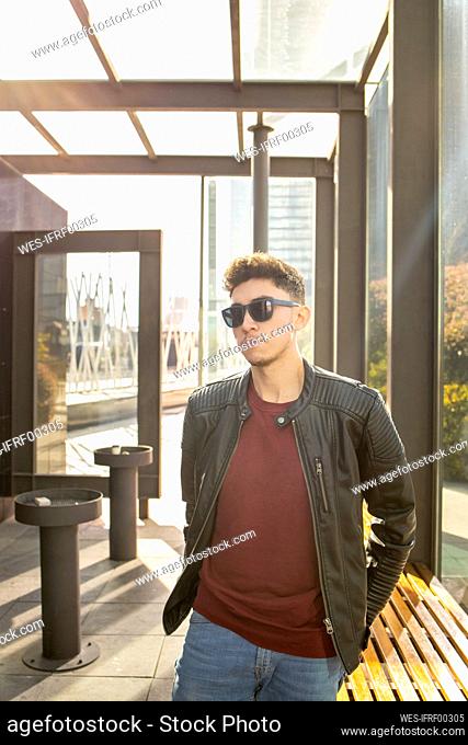 Young man wearing sunglasses looking away while standing in lobby