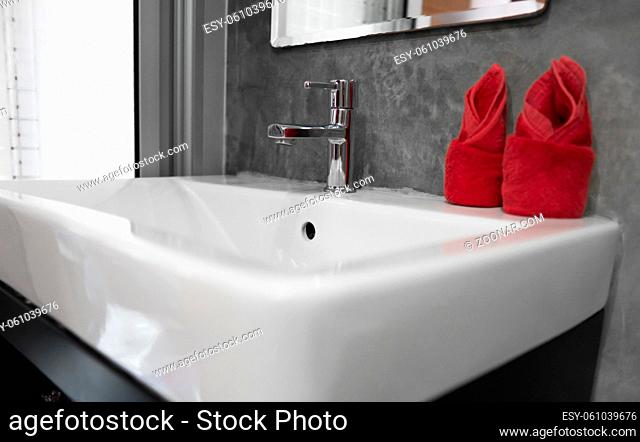 Modern stainless steel faucet with wash basin sink with a two red towels on it . Counter bathroom interior contemporary. Luxury and stylish design bathroom with...