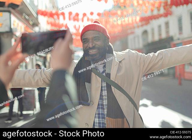 Woman photographing happy man on sunny city street