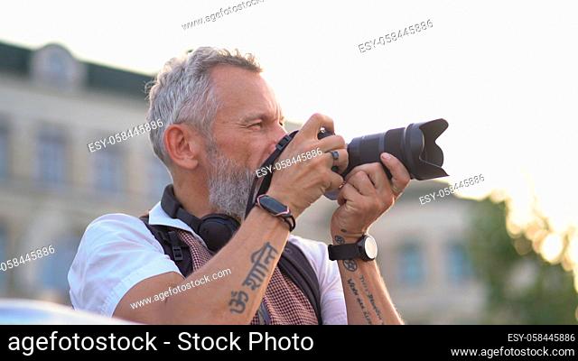 European handsome carefully chooses the frame to pull the trigger of the camera. Photographer at work. Profile view