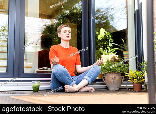 Mid adult woman meditating while sitting against house in porch