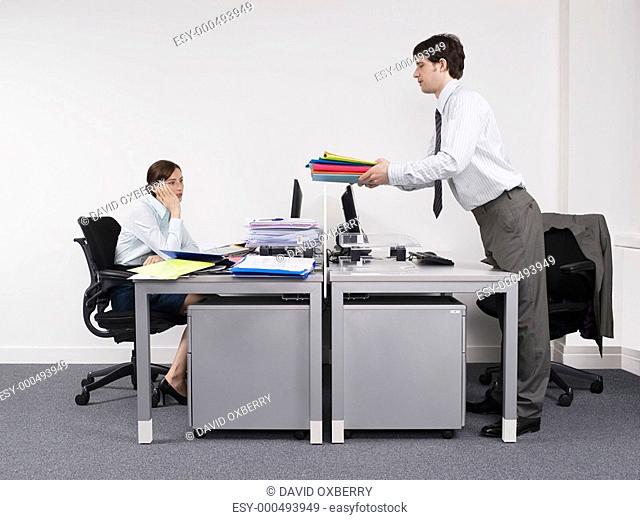 Businessman passing off work to female colleague in office