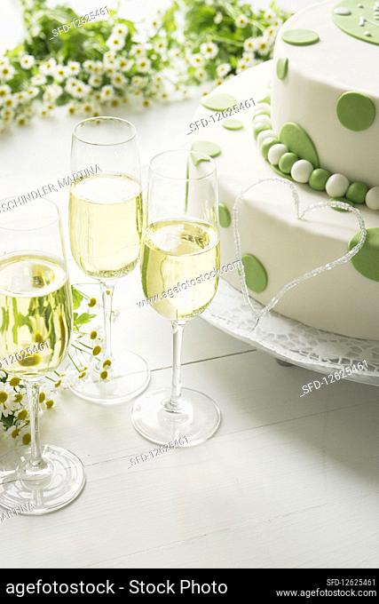 Butter cream cake with fondant for a birthday, with chamomile flowers and champagne glasses
