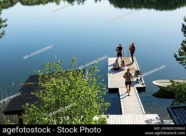 Group of friends with babies standing on deck at lake