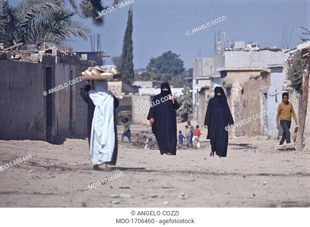 Women on the streets of Gaza. Some women carry the bread and walk in the streets of Gaza wearing the chador. Gaza, Palestinian State, 1970