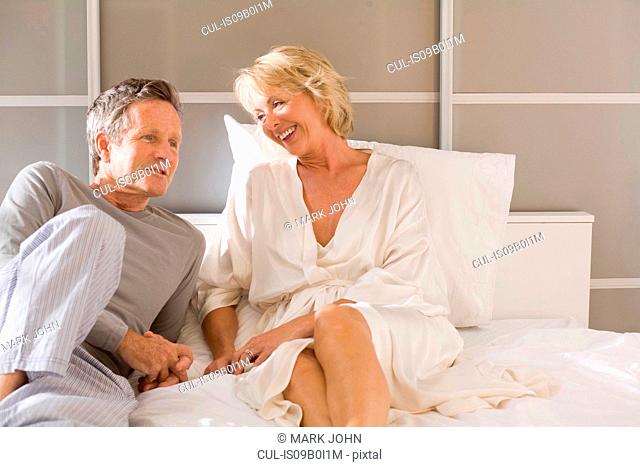 Couple reclining on bed chatting