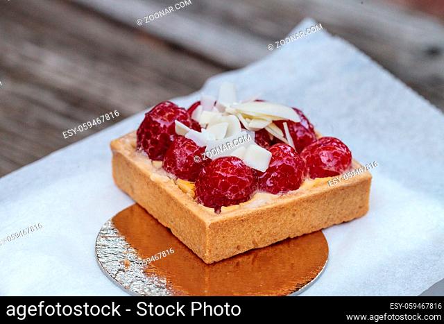 Red raspberry tart pastry with a cookie crust and white chocolate flakes in bakery