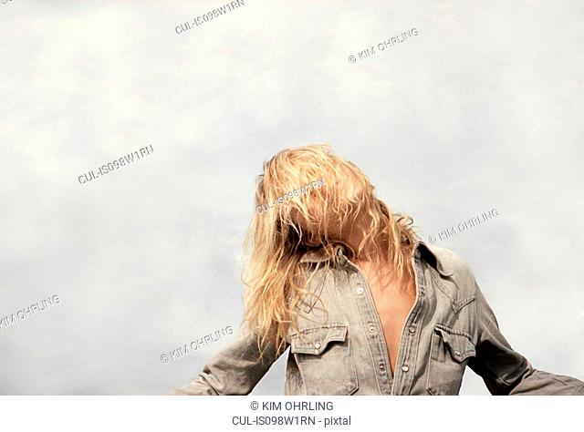Young woman with blond hair covering face
