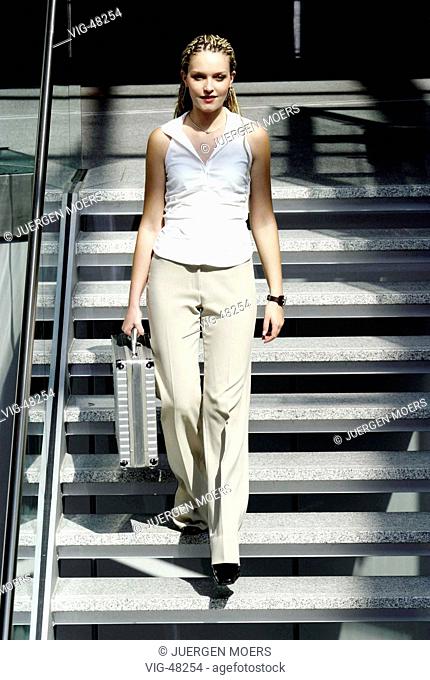 Young woman ( businesswoman ) with a case going down the stairs. - DUESSELDORF, GERMANY, 06/08/2003