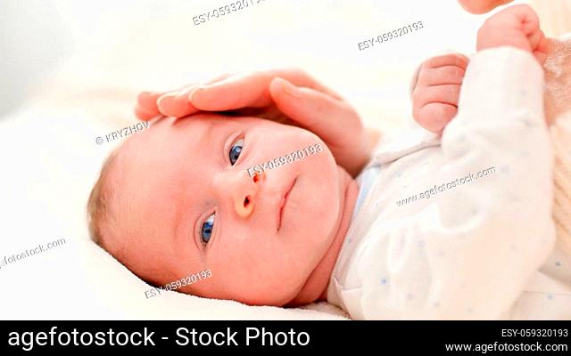 Closeup shot of happy smiling mother and adorable newborn baby boy lyin in crib against big window. Concept of family happiness and loving parents with little...