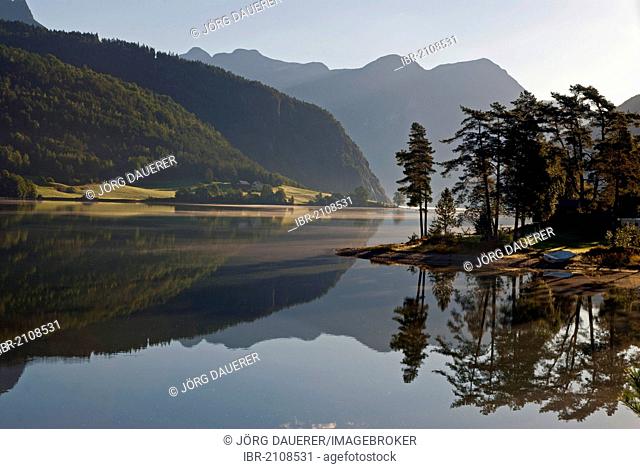 Trees at the shore of lake Strynevatnet, reflected in the calm water, Storesunde, Sogn og Fjordane, Norway, Europe