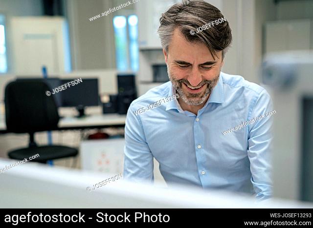 Happy mature businessman at desk in office