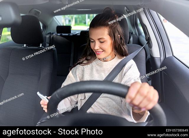 smiling woman or female driver driving car in city