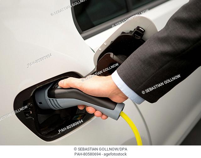 A man plugs a charging plug into an electric Volkswagen Golf at a charging station in the VW plant in Wolfsburg, Germany, 20 May 2016