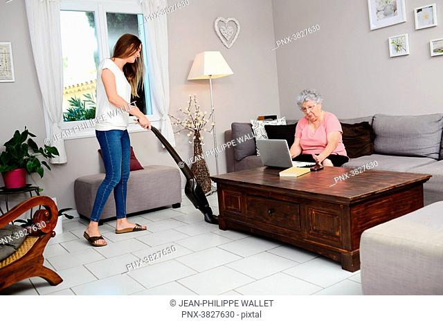 Cheerful young girl helping with household chores elderly woman at home