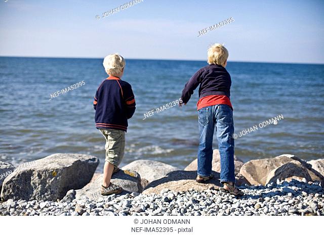Two boys throwing stones into the water, Gotland, Sweden
