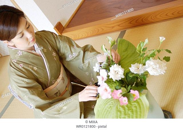 A woman in kimono arranging flowers