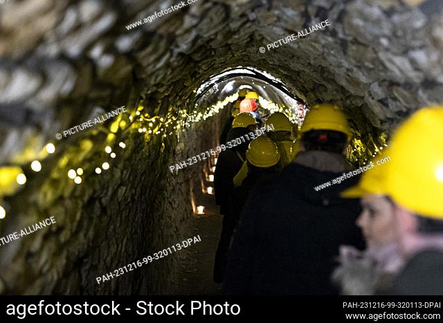 16 December 2023, Lower Saxony, Goslar: Visitors wearing hard hats walk through the Christmas-lit ""Röder"" gallery, which is part of the Rammelsberg Mining...