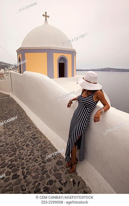 Woman in front of a yellow domed church in Fira town, Santorini, Cyclades Islands, Greek Islands, Greece, Europe